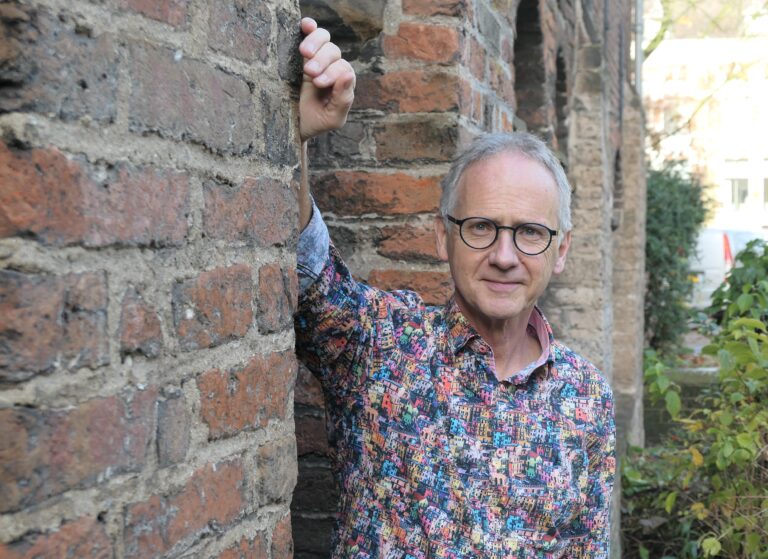 man, decaan, leunt tegen muur