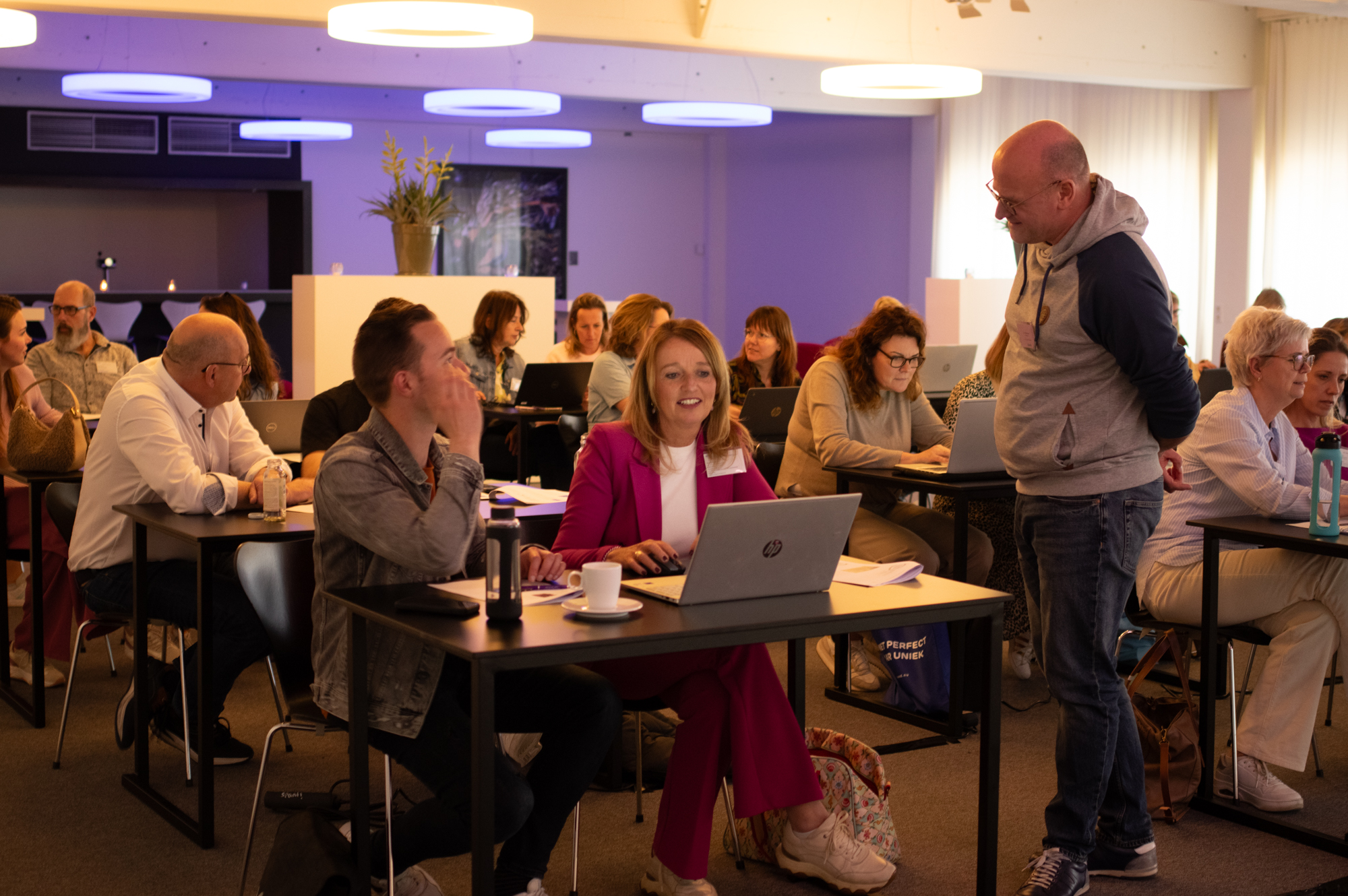 Groep volwassenen zitten met laptops aan tafel tijdens deelsessie _ BiOND Congres