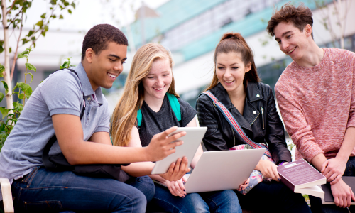 Jongeren zitten buiten met iPad en laptop