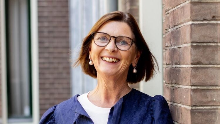 vrouw met bril en parel oorbellen lacht in camera